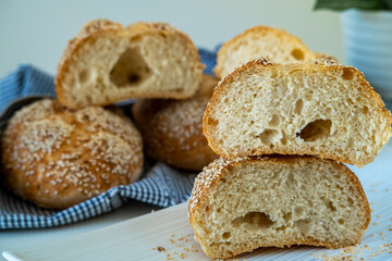 Fresh challah bread rolls hot from the oven cut into half. Crumb shot of gluten free bread buns or mini loaves with sesame seeds and golden color. Fluffy homemade bread wrapped in a towel ready to eat