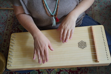 Caucasian woman holding a monochord, sound healing instrument in a therapy session, hands close up.
