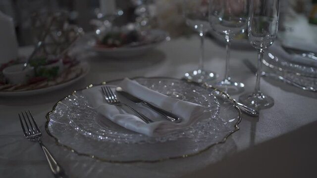 Festive table setting. Glasses and plates on a banquet table. Night Party at a fancy restaurant. Celebration event on holidays. Beautiful decoration with candles on tables. Gourmet and luxury dinner.