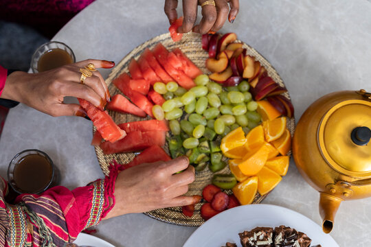 Women with henna on fingers eating fruit from fruit platter