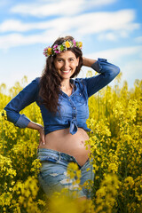 Naklejka na ściany i meble Pregnant woman in a canola field