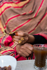 Black Muslim women wearing gold rings holding a date