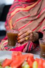Black Muslim woman holding a cup of coffee with gold jewellery on hand