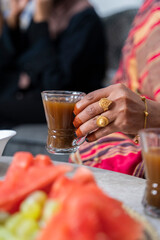 Black Muslim woman holding a cup of coffee with gold jewellery on hand