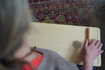 Caucasian woman holding a monochord, sound healing instrument in a therapy session, hands close up.