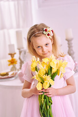 Obraz na płótnie Canvas Girl with yellow bouquet of 7 years in pink dress with beautiful hairstyle smiles