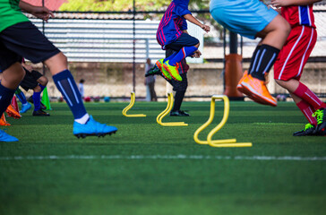 Obraz premium Soccer ball tactics on grass field with barrier for training children jump skill