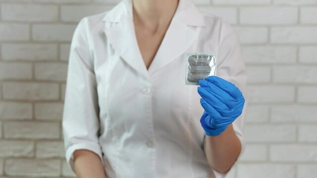 Doctor with a condom. A woman doctor hold a condom in her hands. A concept of contraception in woman's life.