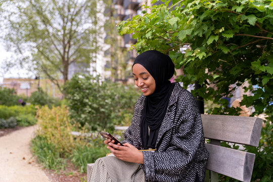 Black Muslim woman on a park bench