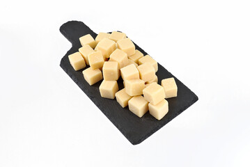 Parmesan  cubes on a slate serving plate with cutting board shape. It is a hard granular cheese of North italy.   White background.	