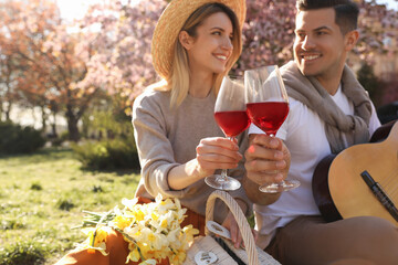 Lovely couple having picnic in park, focus on hands with glasses of wine