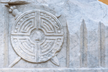 Close-up on ancient shield with swords carved on marble wall