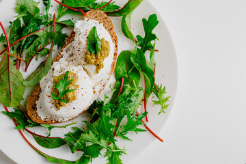 Avocado egg benedict with cream cheese Philadelphia. Poached eggs on healthy bread toast with hollandaise sauce. Cut egg. The yolk flows out. Green salad arugula leaves.