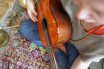 Girl with guitar sitting on the floor in Yogi pose.