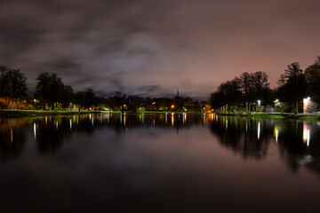 Night landscape. A lake with wonderfully calm water which reflects the lanterns of the park.
