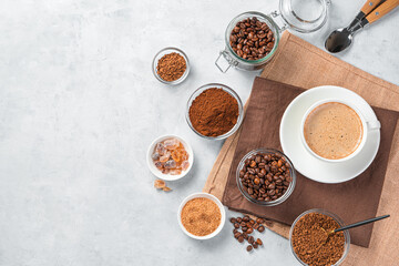 Grain, ground and instant coffee and a cup of coffee on a gray background.