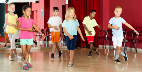 Group of smiling little boys and beautiful girls having a dancing class in the studio