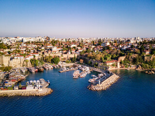 Fototapeta na wymiar Aerial photograph of Antalya bay in Antalya city from high point of drone fly on sunny day in in Turkey. Amazing aerial cityscape view from birds fly altitude on beautiful town and sea full of yahts