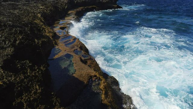Slow aerial rise above natural ocean pools at Cap Des Pins, New Caledonia.
