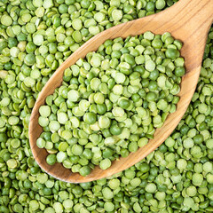 green split peas in wooden spoon closeup