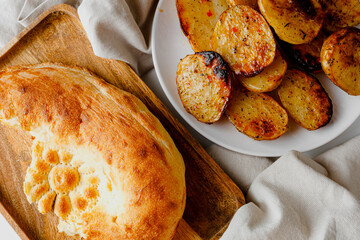 Tasty fried potatoes with parsley, closeup. Fresh backed bread.