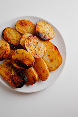 Tasty fried potatoes with parsley, closeup. Fresh backed bread.