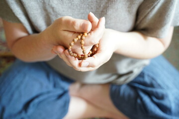A  woman holding a mala yoga prayer bead necklace in her hand.