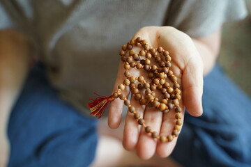 A  woman holding a mala yoga prayer bead necklace in her hand.