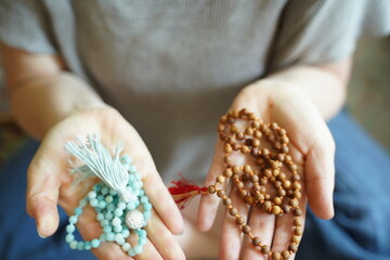 A  woman holding a mala yoga prayer bead necklace in each hand.