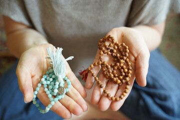 A  woman holding a mala yoga prayer bead necklace in each hand.