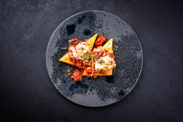 Modern style traditional Italian polenta alla sarda con salsiccia with meat sausage served as top view on a Nordic design plate with copy space
