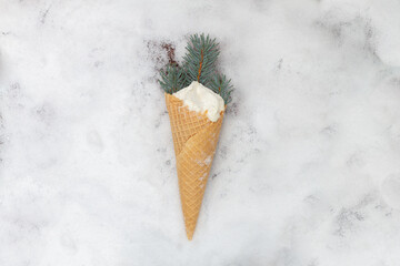 Ice cream cone in the snow in the cold winter with branches of a Christmas tree