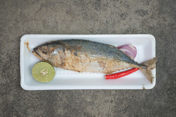 Steamed short mackerel served with red onion, lemon and red chili in foam tray.