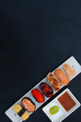 The sushi set is a famous Japanese dish, put on a ceramic plate, beautifully arranged on a black background.