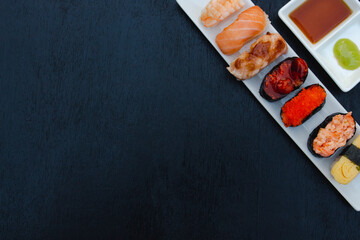 The sushi set is a famous Japanese dish, put on a ceramic plate, beautifully arranged on a black background.