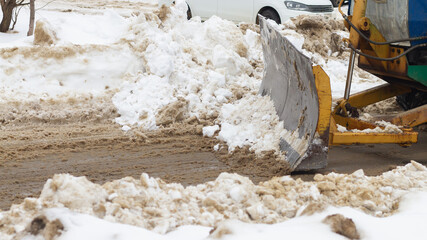 Tractor clears snow with a bucket in winter on the road with a bucket