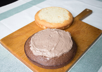 The process of making a cake at home. Household chores. A fresh homemade cake is on a wooden board. two sponge cakes, a cream layer, chocolate ganache. Series of photos with a step-by-step recipe