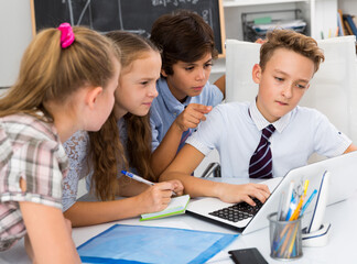 Group of children near laptop talking about mathematics indoors