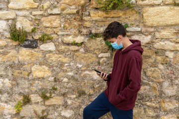 Fototapeta premium boy with mask using mobile phone