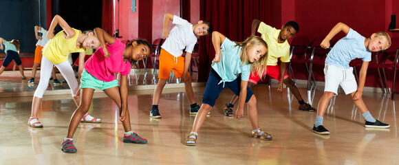 Focused kids studying modern style dances in dance class indoors
