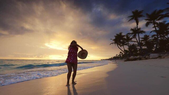 Caribbean life on a tropical island. Girl relaxing on exotic beach with palm trees on sunrise.