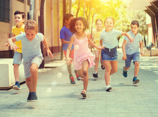 Obraz premium Group of joyful children running down the summer city street