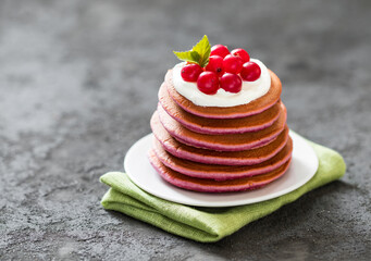 Breakfast, berry pancakes with cream on a plate on a linen napkin on a dark gray background