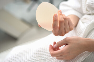 Close-up Hand of young woman patient preparing for breast augmentation with silicone breast...