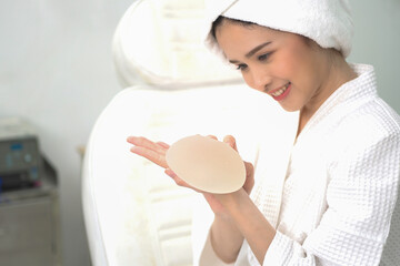 Hand of young woman patient preparing for breast augmentation with silicone breast augmentation is...