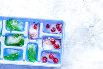 Obraz na płótnie Canvas Ice cubes with berries and mint stone background top view mock up