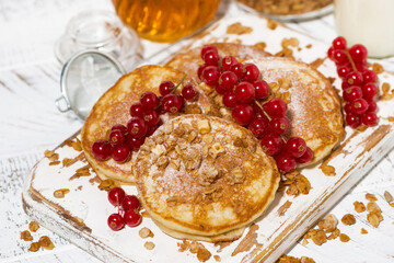 delicious pancakes with berries and honey on a white wooden board