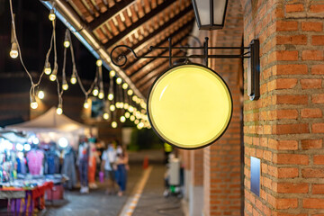 The Circle yellow Lightbox has hung on the wall in front of the brick pole in a Tungsten ambient environment vintage shopping community mall.