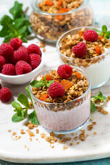 sweet dessert with granola, fresh raspberries, fruit and natural yoghurt, vertical