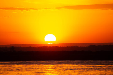 orange sunset by the water, the sun in the sky 